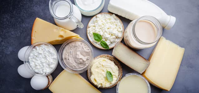 Fresh dairy products, milk, cottage cheese, eggs, yogurt, sour cream and butter on black background, top view